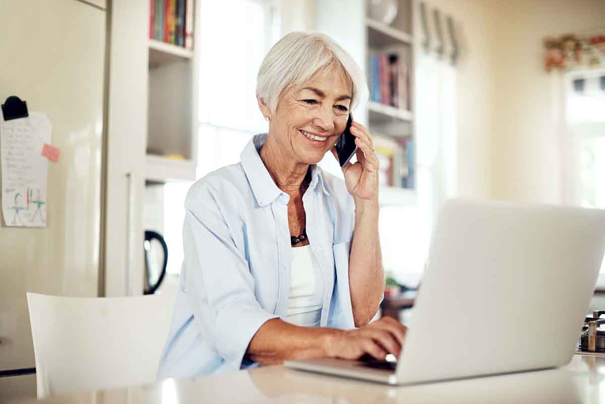senior woman on phone using laptop