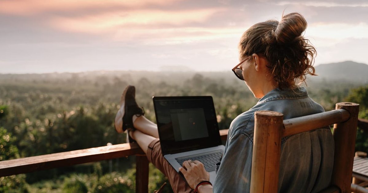 woman sitting at a laptop on a balcony